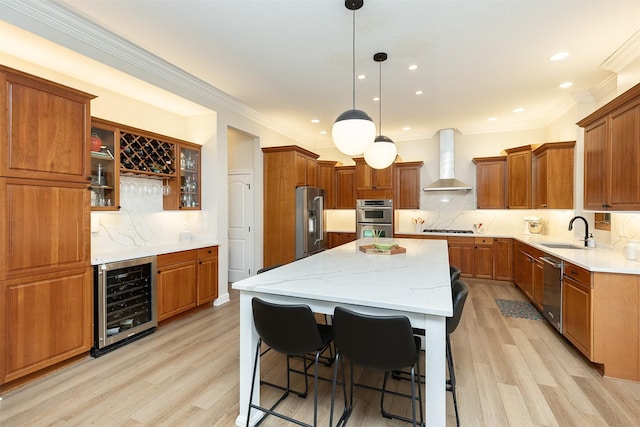 kitchen featuring wall chimney range hood, appliances with stainless steel finishes, a center island, a sink, and wine cooler