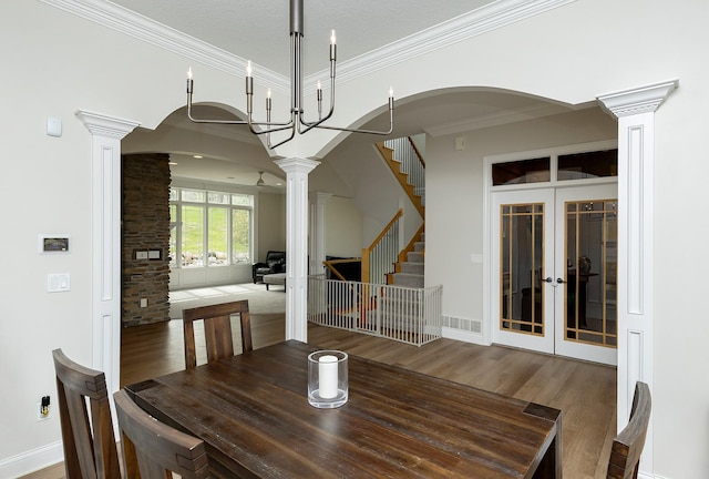 unfurnished dining area featuring crown molding, french doors, wood finished floors, ornate columns, and stairway