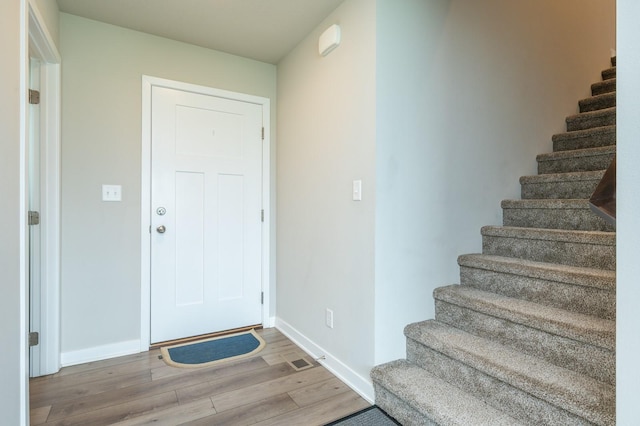 entrance foyer featuring baseboards, wood finished floors, and stairway
