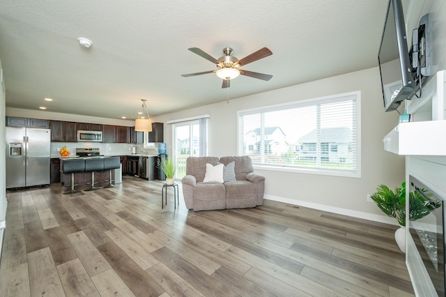 living room with light wood-style floors, baseboards, ceiling fan, and recessed lighting