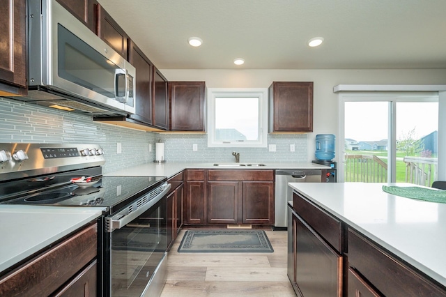kitchen featuring dark brown cabinetry, appliances with stainless steel finishes, a sink, light countertops, and light wood-type flooring
