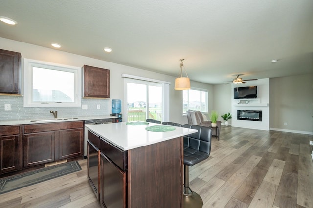 kitchen featuring a breakfast bar area, a center island, light wood-type flooring, a sink, and light countertops