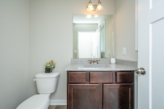 half bath with vanity, wood finished floors, and toilet
