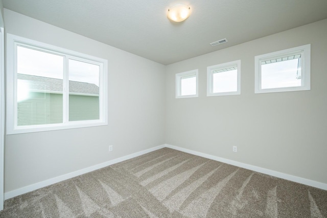 carpeted spare room featuring baseboards and visible vents