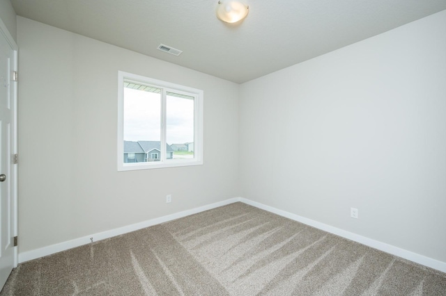spare room with visible vents, carpet, and baseboards