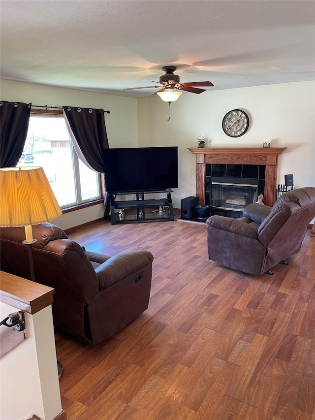 living area featuring a fireplace, a ceiling fan, and wood finished floors