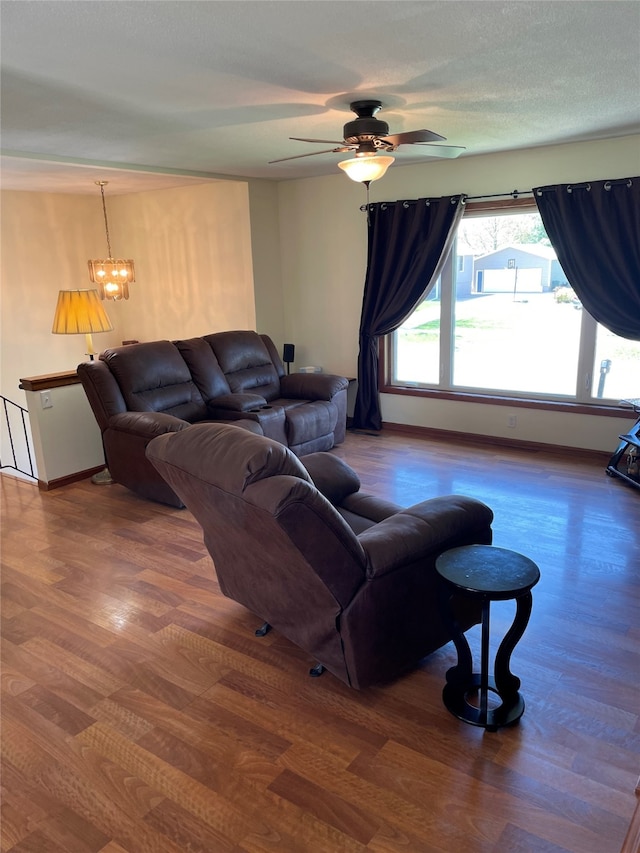 living room with baseboards, ceiling fan with notable chandelier, and wood finished floors