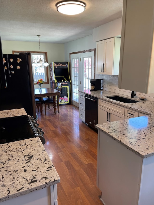 kitchen with black appliances, dark wood-style flooring, white cabinetry, and a chandelier
