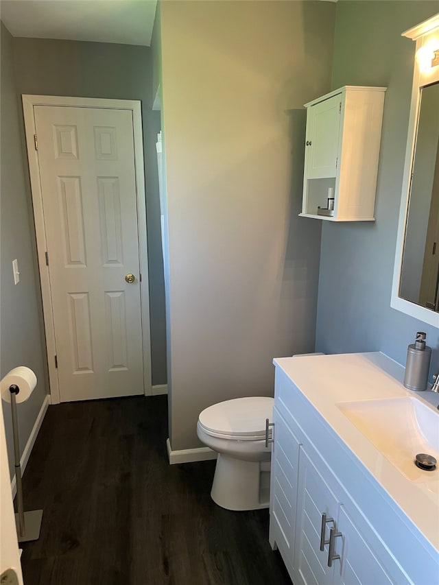 bathroom with baseboards, vanity, toilet, and wood finished floors