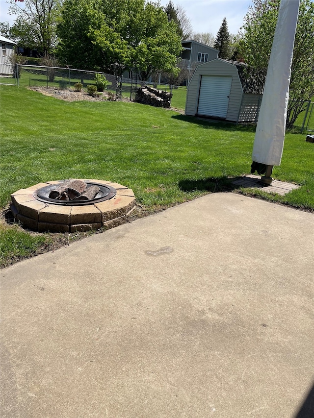 view of yard featuring fence, a storage unit, an outdoor fire pit, a patio area, and an outdoor structure
