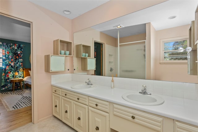 ensuite bathroom with double vanity, ensuite bath, a sink, and a stall shower