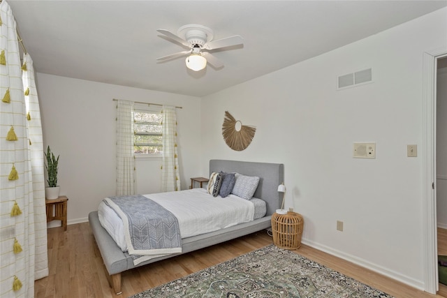 bedroom featuring visible vents, a ceiling fan, baseboards, and wood finished floors