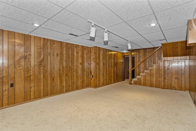 finished below grade area with stairway, carpet flooring, and wood walls