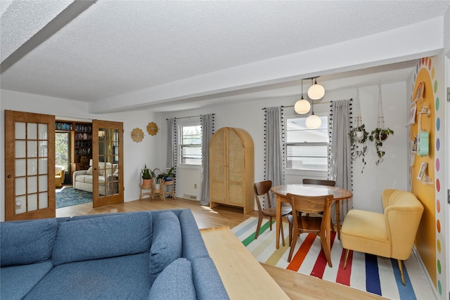 living room featuring french doors, a textured ceiling, and light wood finished floors