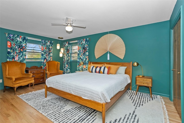 bedroom featuring baseboards, a ceiling fan, and light wood-style flooring