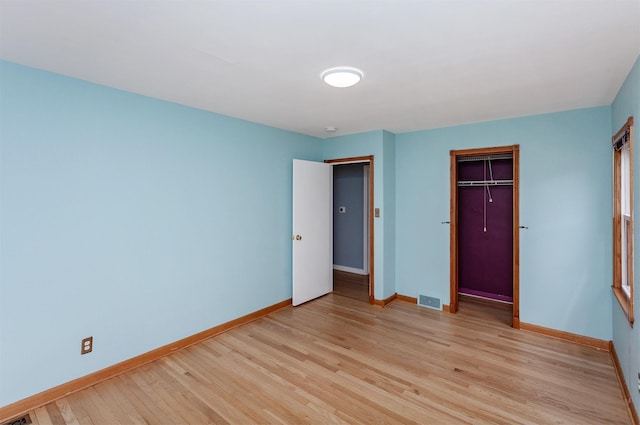 unfurnished bedroom featuring baseboards, visible vents, light wood-style flooring, and a closet