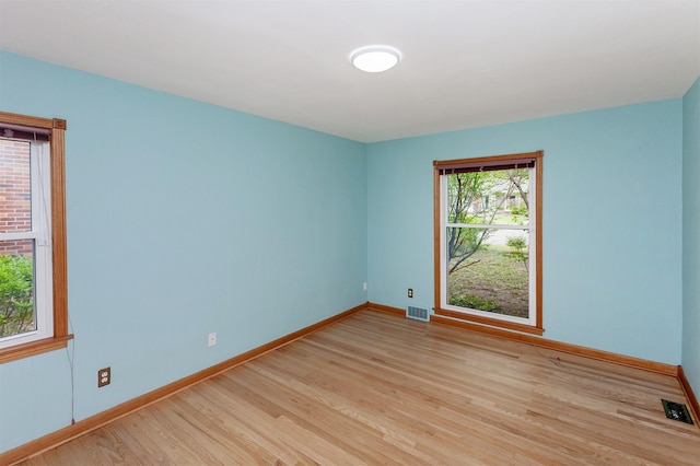 unfurnished room featuring baseboards, visible vents, and light wood finished floors