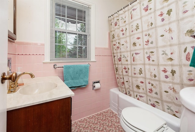 full bathroom featuring vanity, wainscoting, toilet, and tile walls