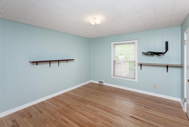spare room with visible vents, baseboards, and wood finished floors