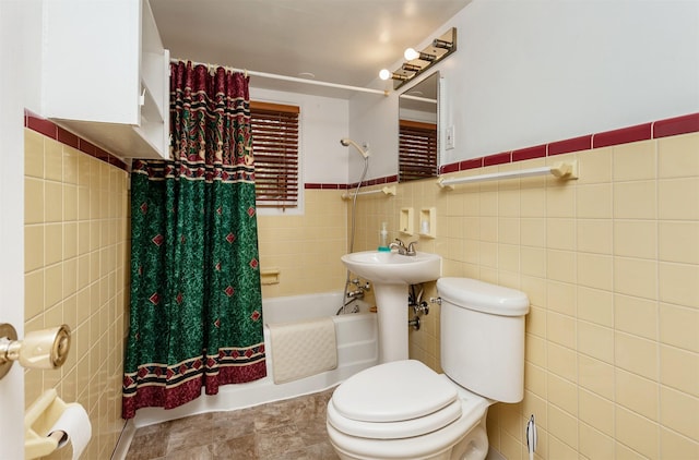bathroom with a sink, toilet, shower / bath combination with curtain, a wainscoted wall, and tile walls