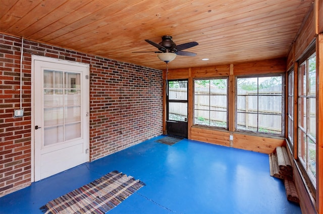 unfurnished sunroom with brick wall, wooden ceiling, and ceiling fan