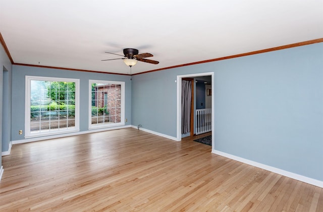 spare room featuring light wood-style floors, baseboards, and crown molding