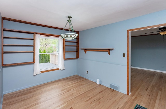 unfurnished room with visible vents, a ceiling fan, baseboards, and wood finished floors