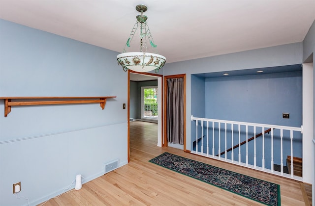 empty room with baseboards, wood finished floors, and visible vents