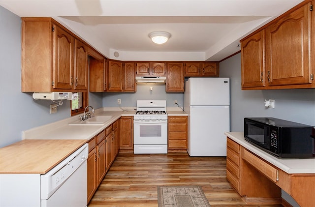 kitchen featuring a sink, white appliances, brown cabinetry, light wood-style flooring, and under cabinet range hood