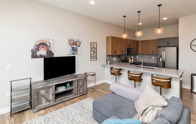 living area with recessed lighting, baseboards, and light wood-type flooring
