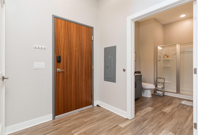 entrance foyer with light wood-style floors, baseboards, and electric panel