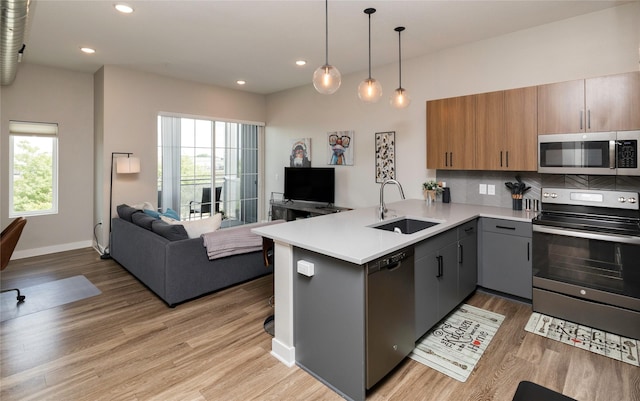 kitchen featuring appliances with stainless steel finishes, a sink, a peninsula, open floor plan, and a wealth of natural light