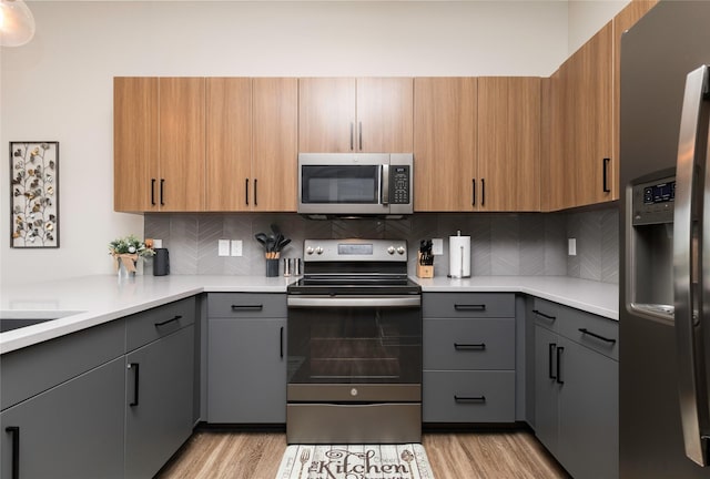 kitchen featuring appliances with stainless steel finishes, gray cabinets, and light wood-type flooring