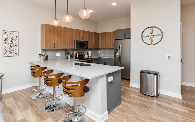 kitchen with a sink, appliances with stainless steel finishes, a peninsula, and light countertops