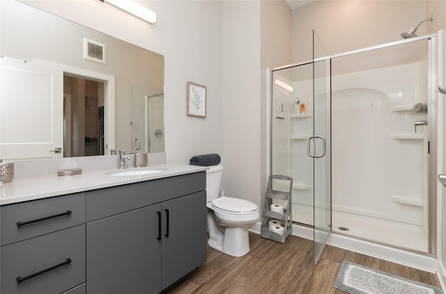 bathroom with visible vents, a shower stall, wood finished floors, vanity, and toilet