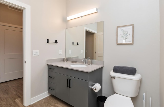 bathroom featuring visible vents, vanity, wood finished floors, toilet, and baseboards