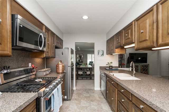kitchen featuring appliances with stainless steel finishes, a sink, recessed lighting, baseboards, and backsplash