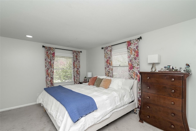 bedroom featuring baseboards, multiple windows, and light carpet