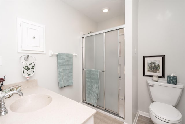 bathroom with vanity, a stall shower, toilet, and wood finished floors
