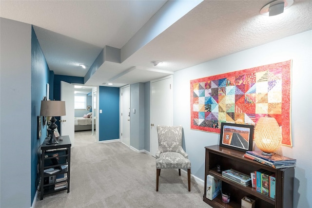 living area featuring baseboards, carpet flooring, and a textured ceiling