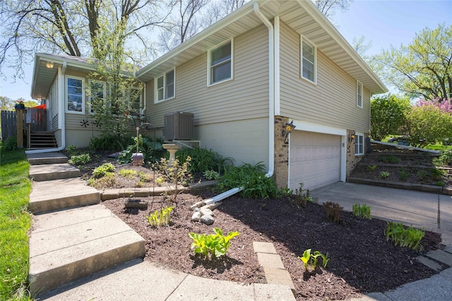 view of home's exterior featuring an attached garage, central AC, driveway, and brick siding