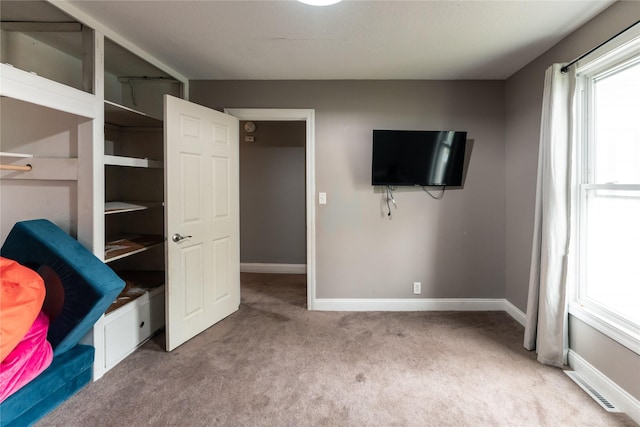 unfurnished bedroom with baseboards, multiple windows, carpet, and visible vents