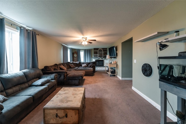 living area with carpet floors, a fireplace, baseboards, ceiling fan, and a textured ceiling