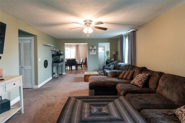 carpeted living area with a ceiling fan, baseboards, and a textured ceiling