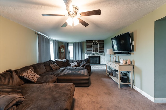 carpeted living area with baseboards, a textured ceiling, ceiling fan, and a large fireplace