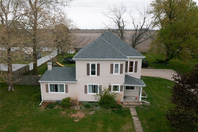 back of property featuring roof with shingles, fence, a chimney, and a yard