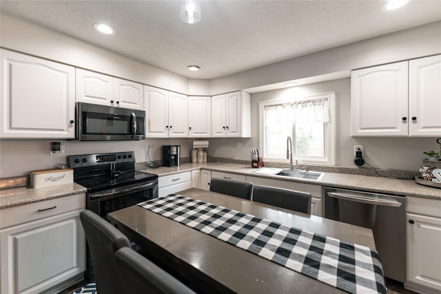 kitchen with a sink, white cabinetry, dishwasher, and black electric range