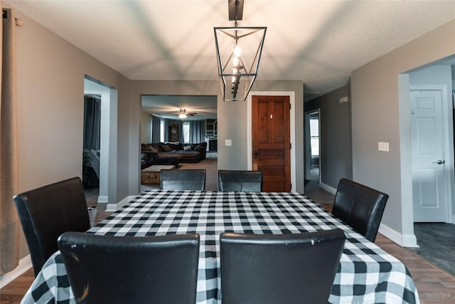 dining area with baseboards, dark wood finished floors, and ceiling fan with notable chandelier