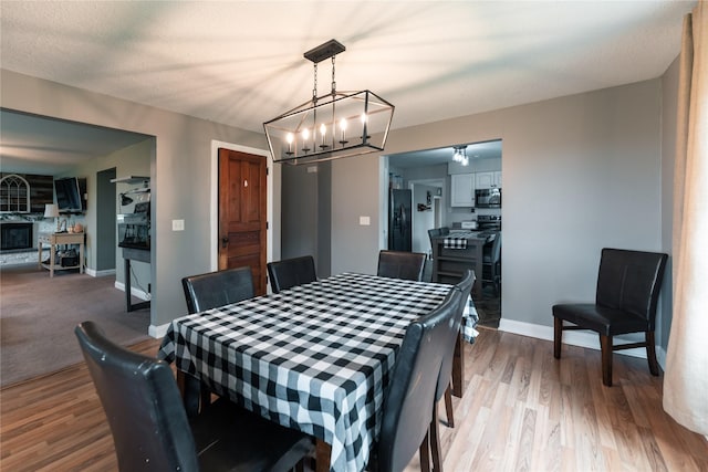 dining area with baseboards, wood finished floors, and a chandelier
