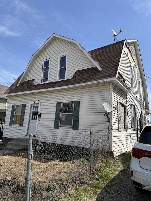 view of front of home featuring roof with shingles, fence, and a gambrel roof